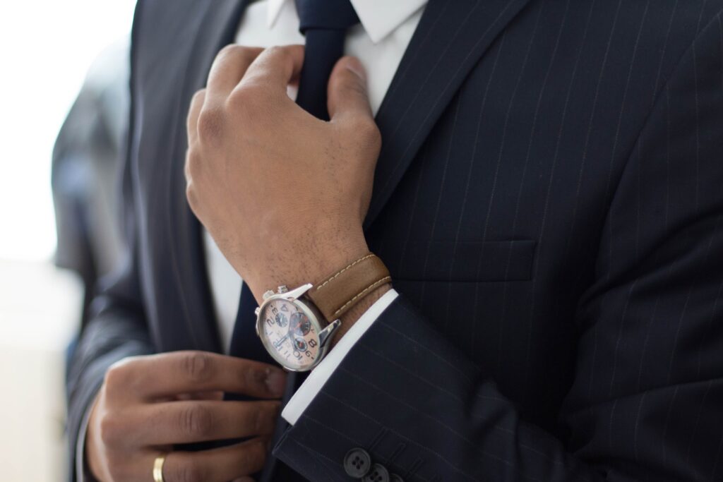 Person wearing a suit and adjusting the tie